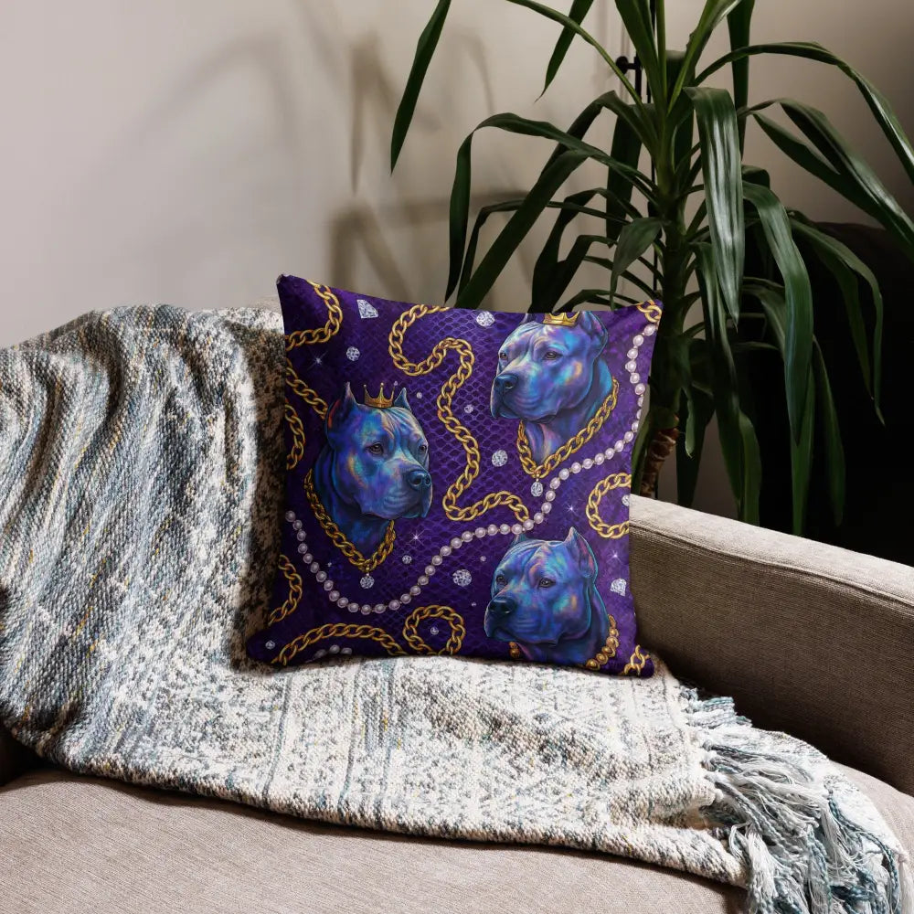 Royal Glam Dog Chains decorative pillow with blue dog heads and gold chain design on a deep blue background placed on a couch with a gray textured blanket and green plant nearby